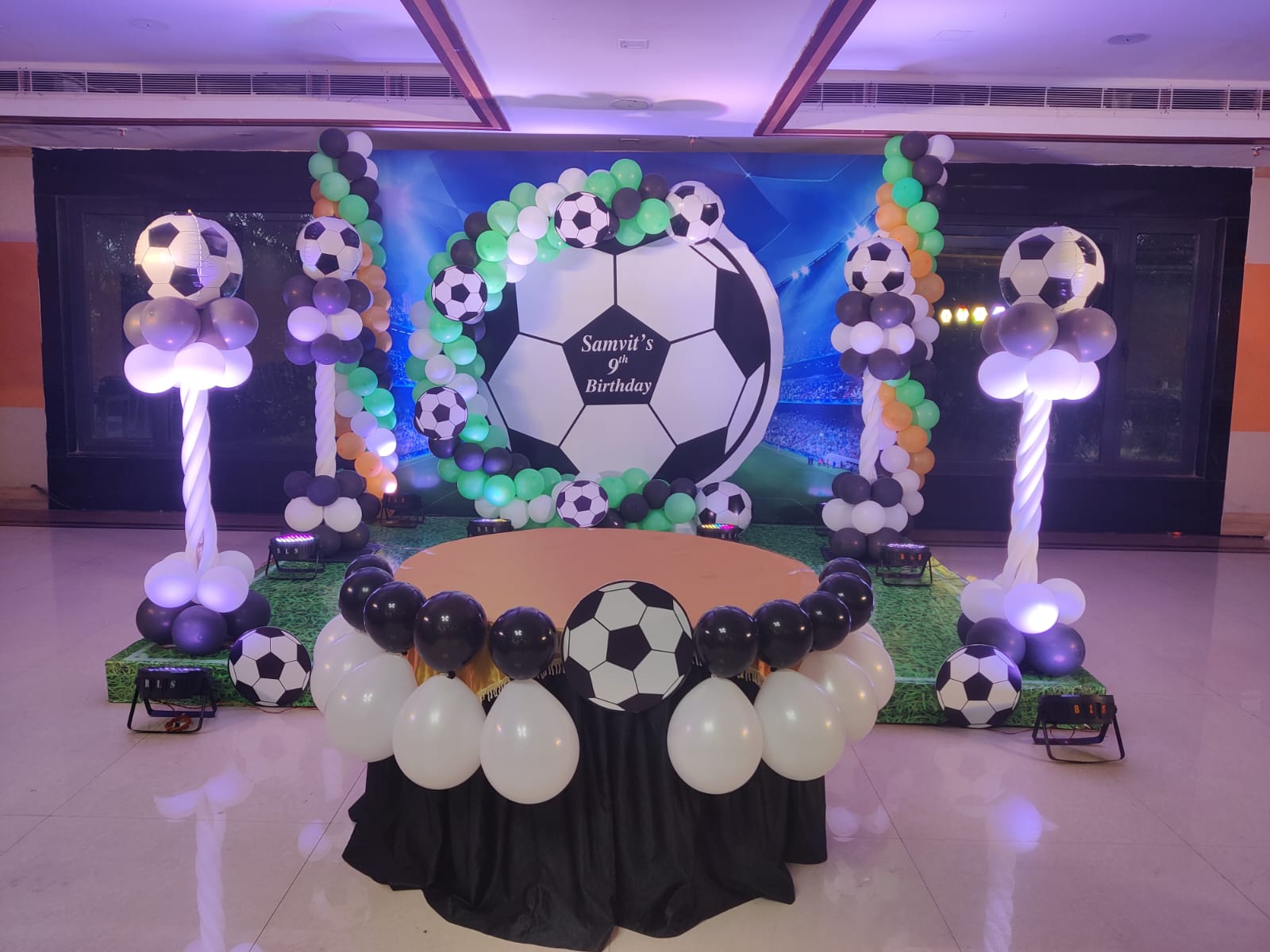 Birthday party decor with blue balloon backdrop and stage lighting